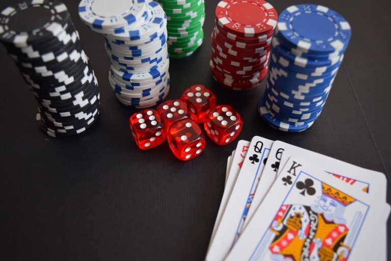 A collection of gaming pieces including chips, dice, and cards displayed on a dark surface