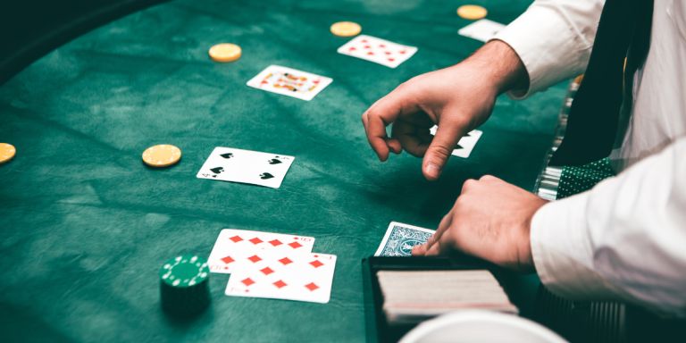 A casino dealer distributes poker cards on a gaming table.